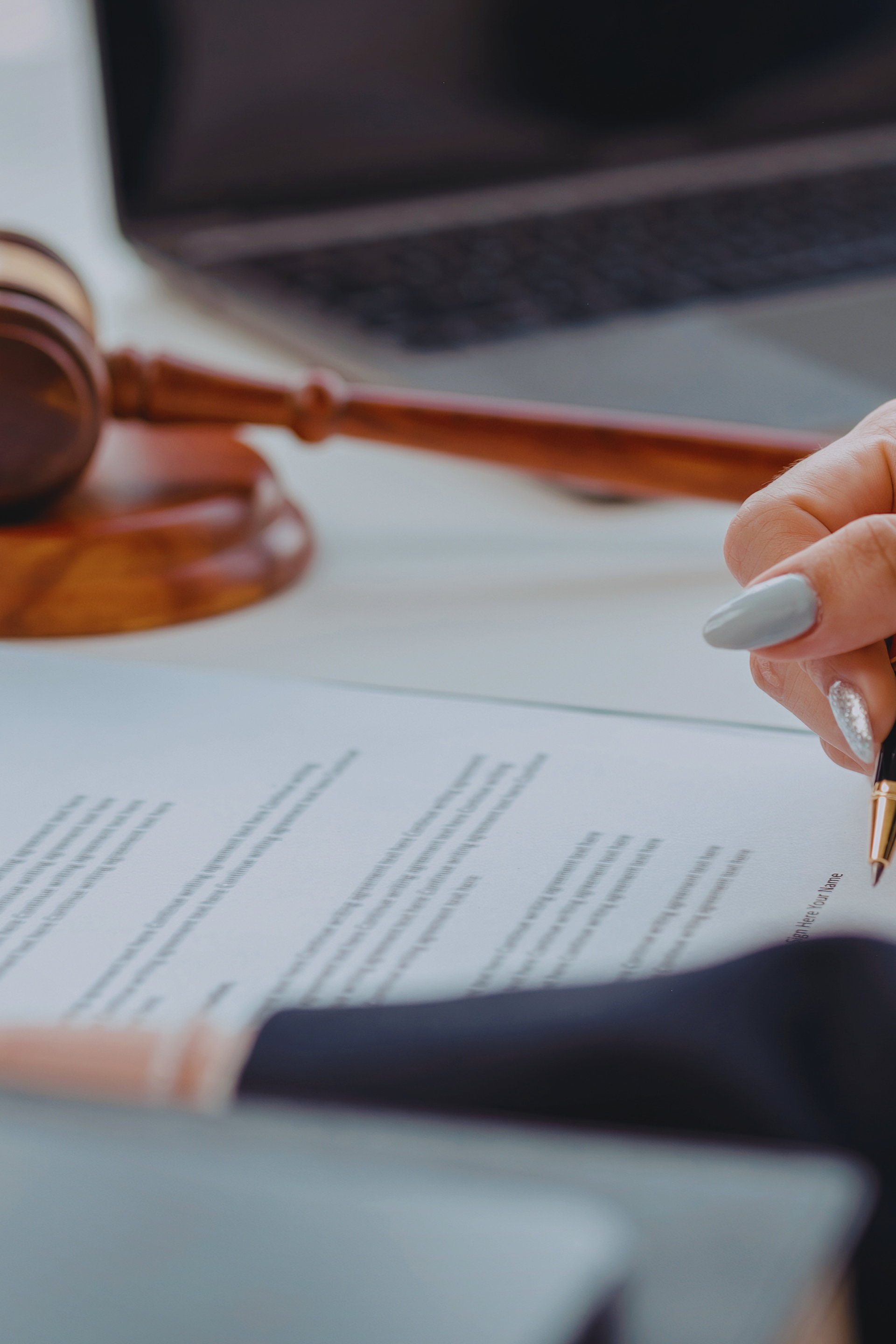 Hand signing a document beside a gavel on a desk