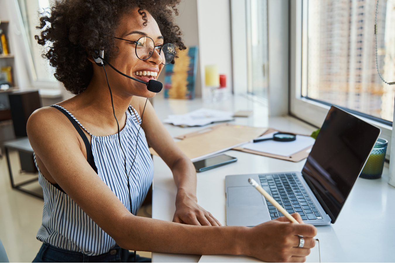 A woman wearing a headset is sitting in front of a laptop computer.