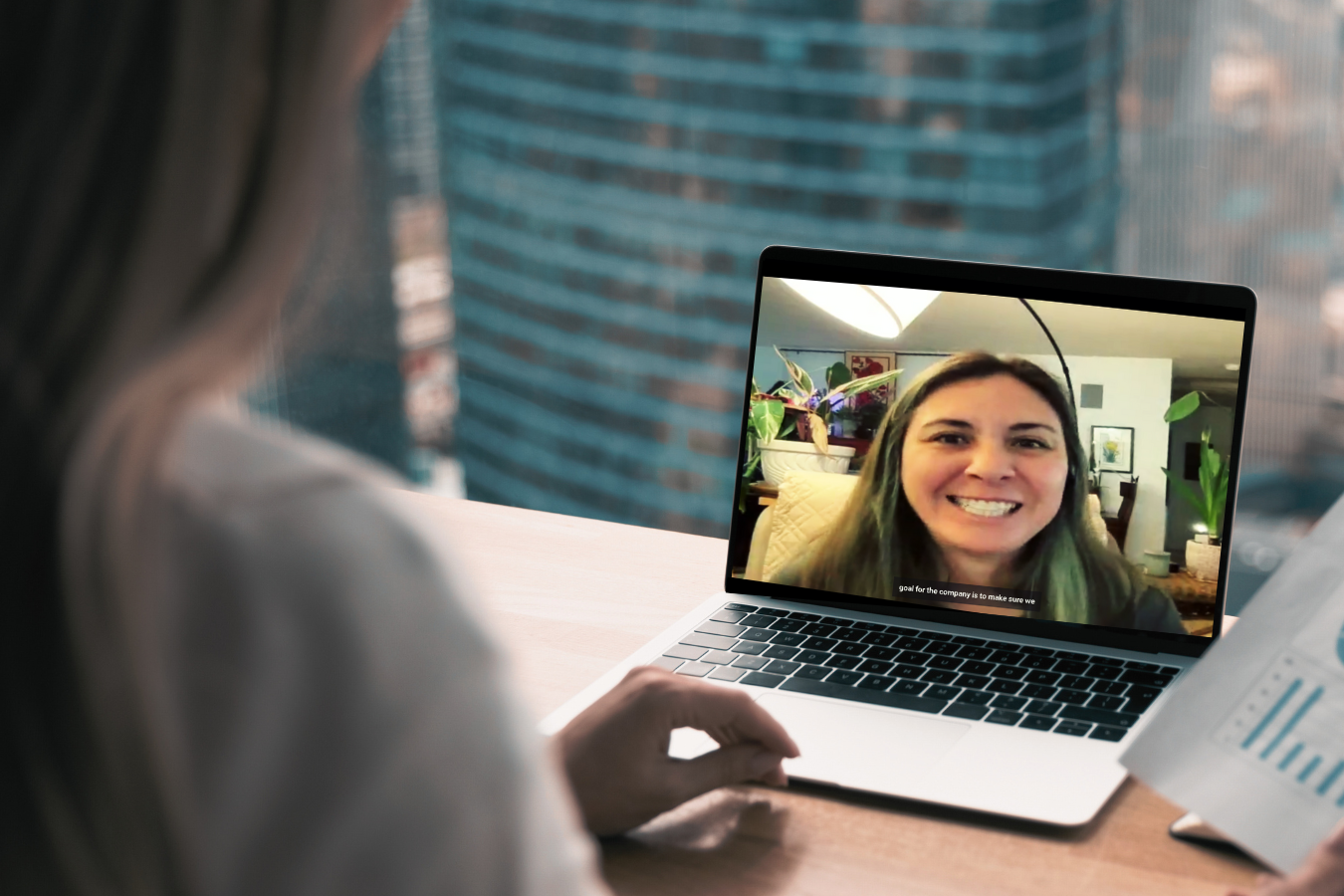 A woman is sitting in front of a laptop computer talking to another woman.