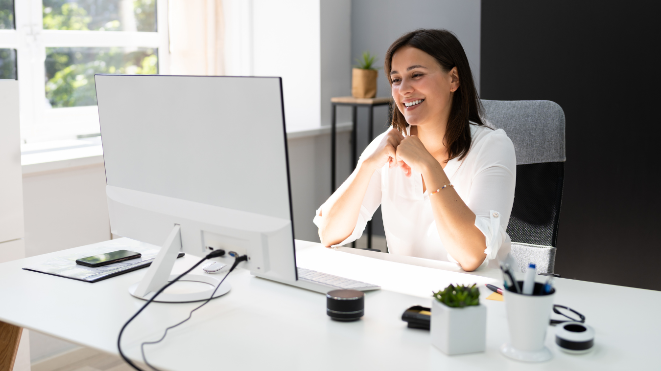 A woman is sitting at a desk in front of a computer.