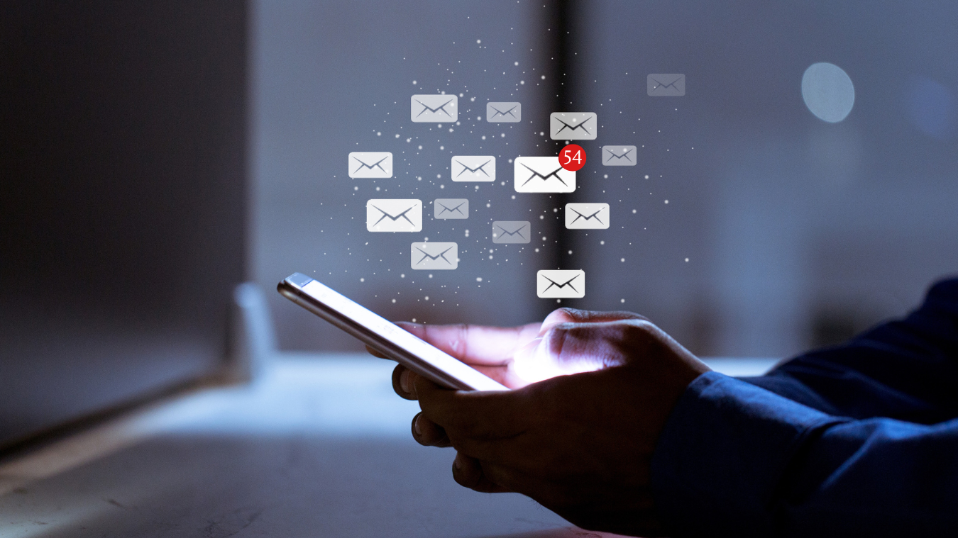 A person is holding a cell phone with a bunch of emails coming out of it.