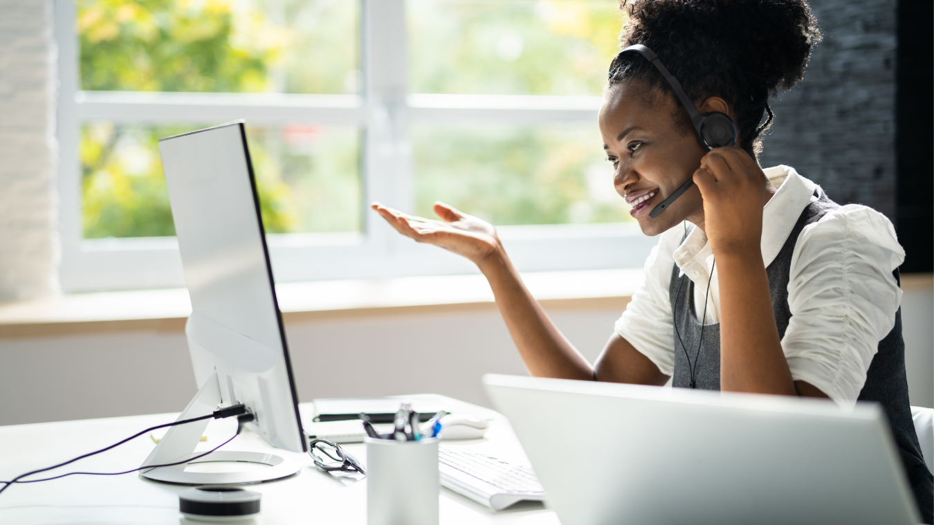 A woman wearing a headset is sitting in front of a computer.