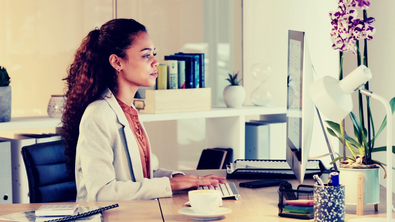 A woman is sitting at a desk in front of a computer.