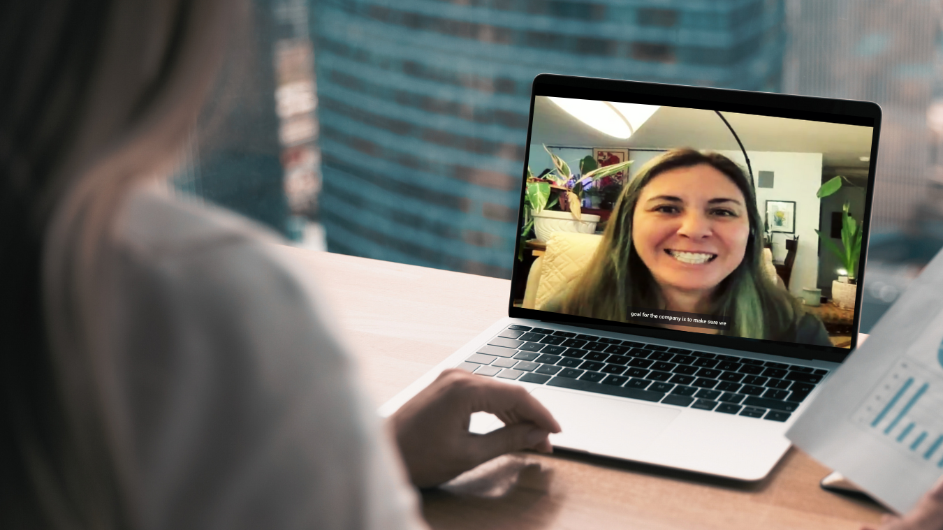 A woman is sitting in front of a laptop computer talking to another woman.