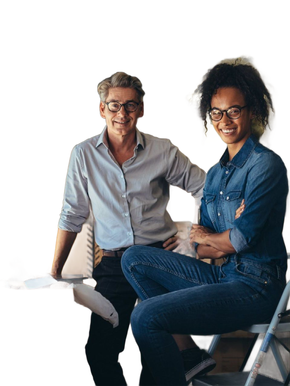 Two smiling coworkers seated on folding chairs against a white background