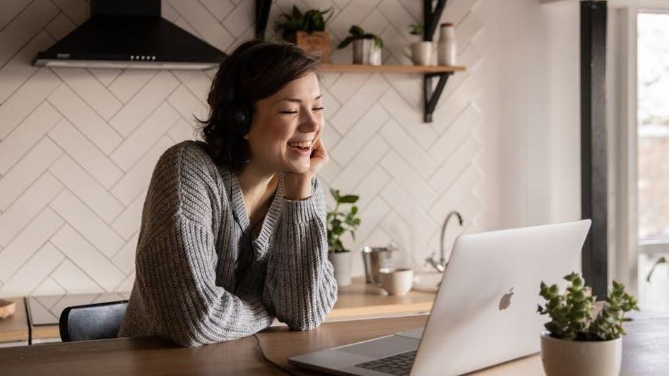 A woman is sitting at a table in front of a laptop computer.