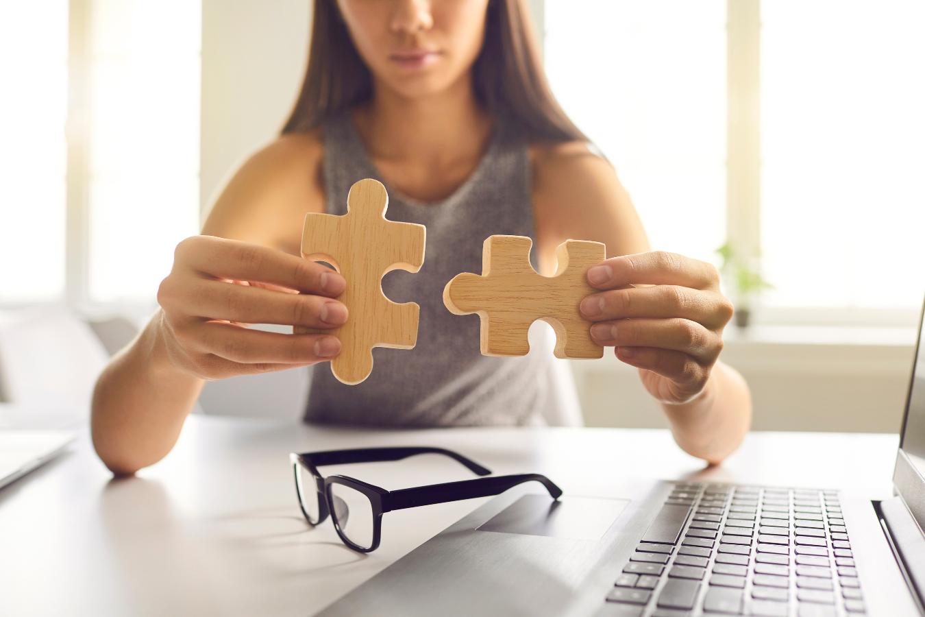 A woman is holding two wooden puzzle pieces in her hands.