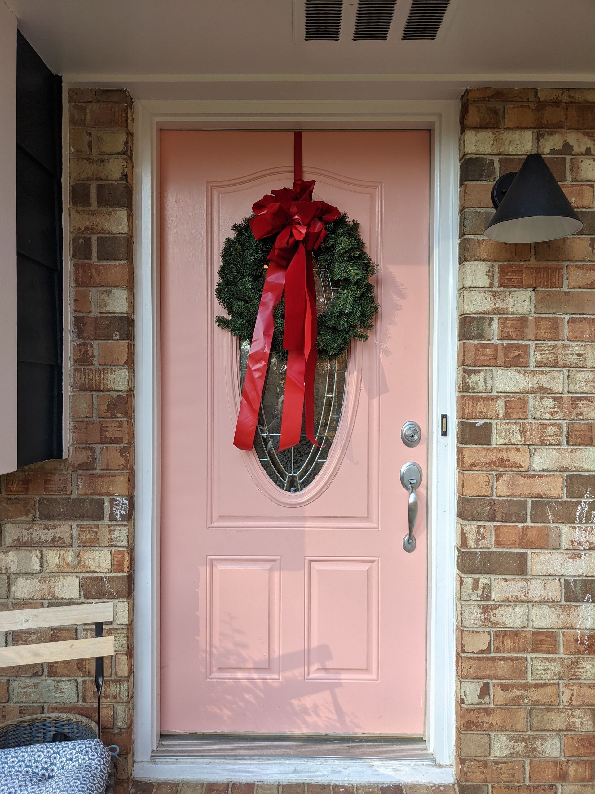 A pink door with a christmas wreath hanging on it