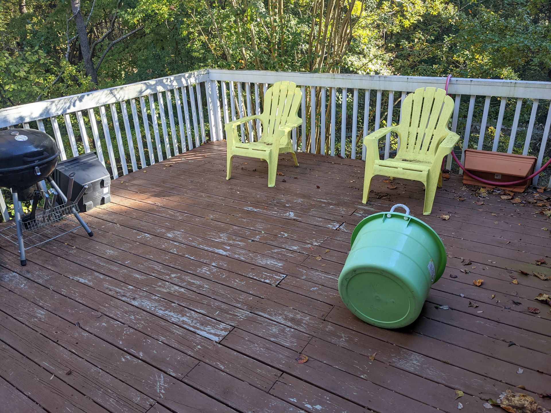 A wooden deck with two yellow chairs and a green bucket on it.