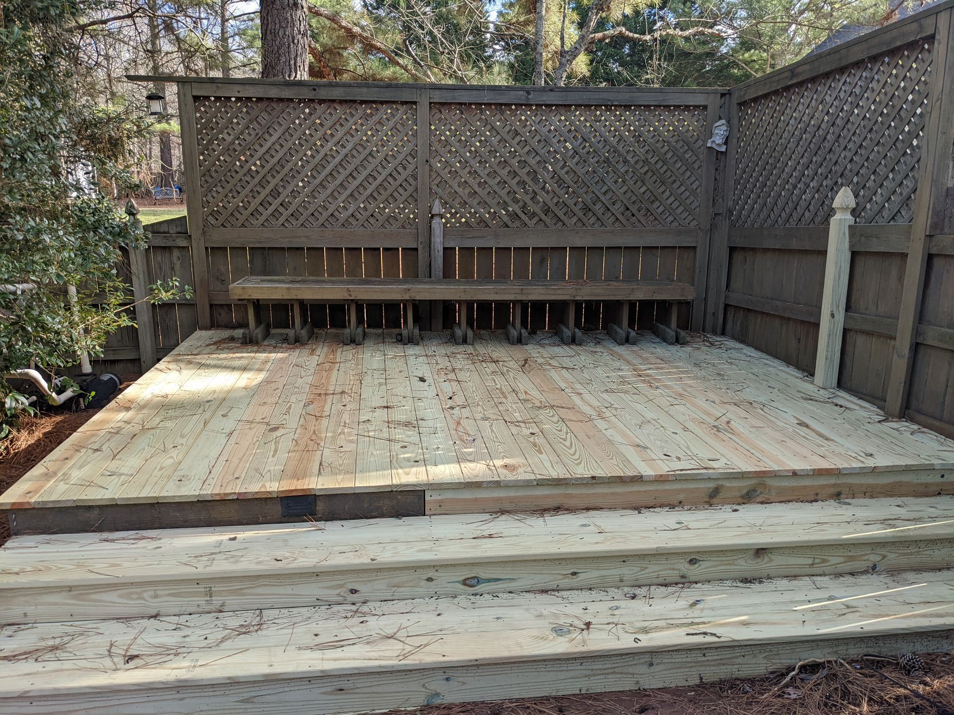 A wooden deck with stairs and a fence in the background.