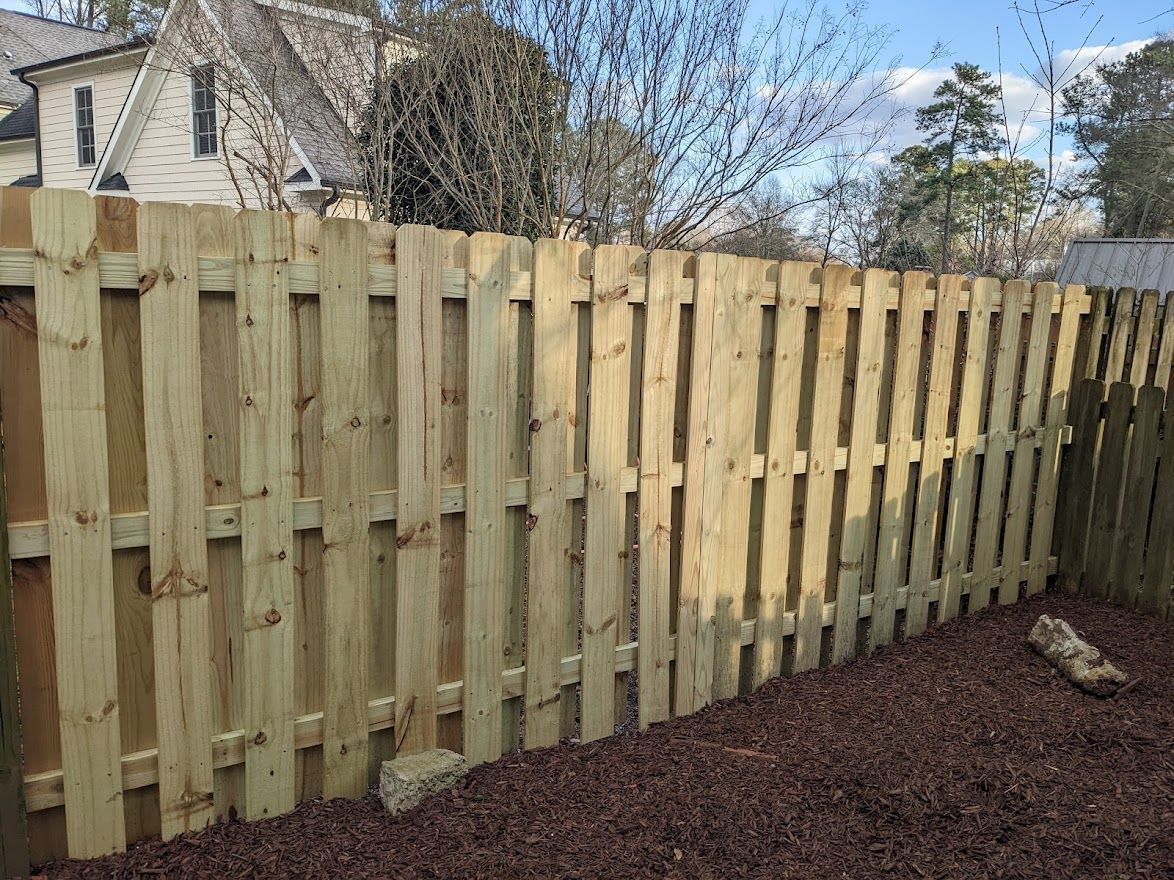 A wooden fence is in the backyard of a house.