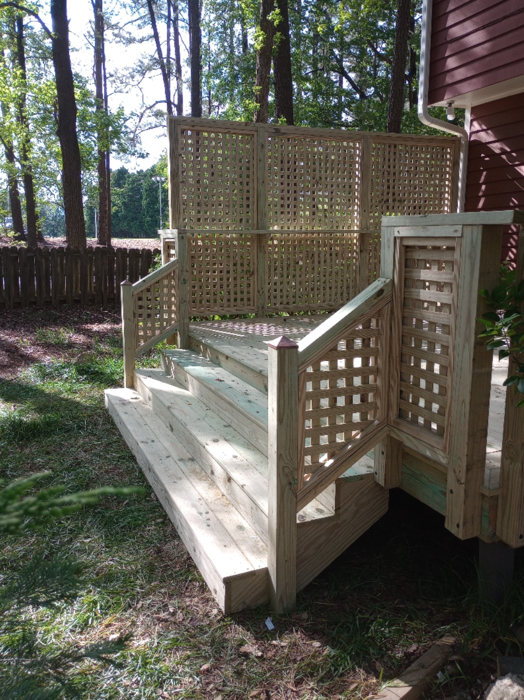 A wooden deck with stairs and a fence in the backyard of a house.