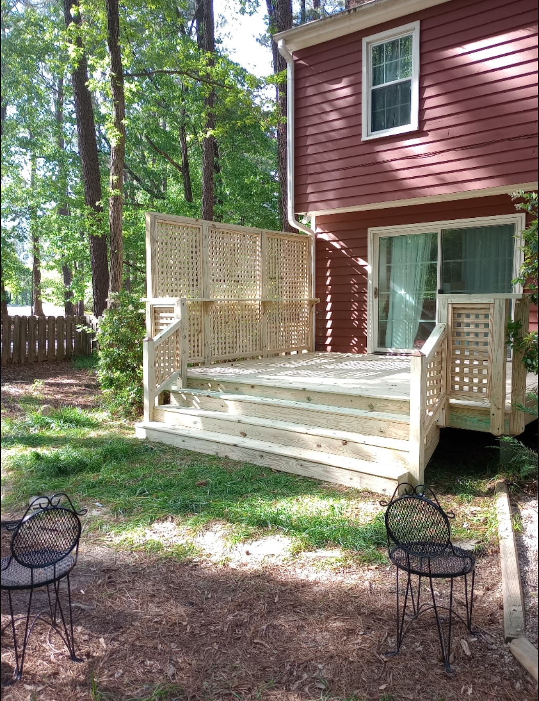 A red house with a wooden deck and chairs in front of it.
