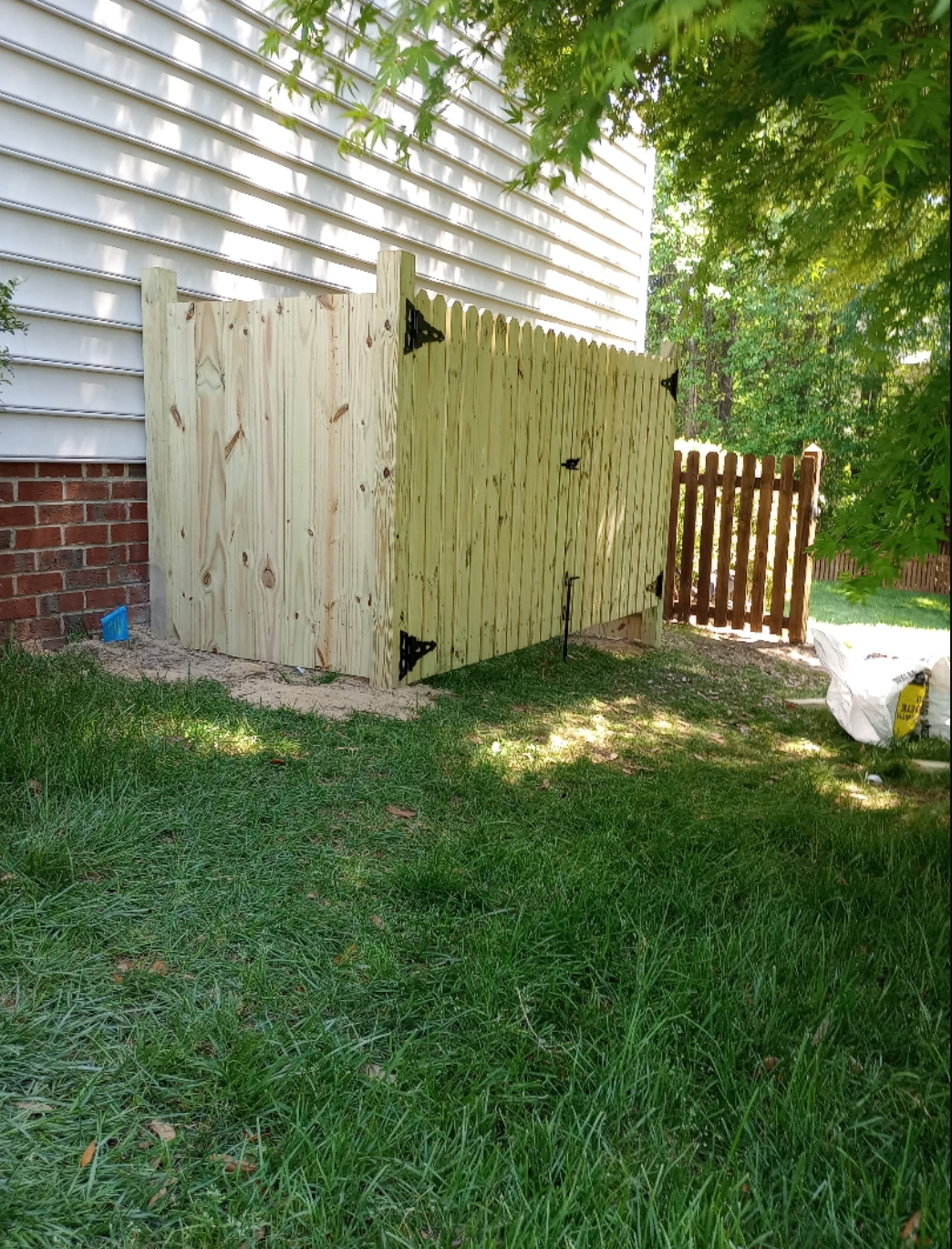 A wooden fence is sitting in the grass in front of a house.