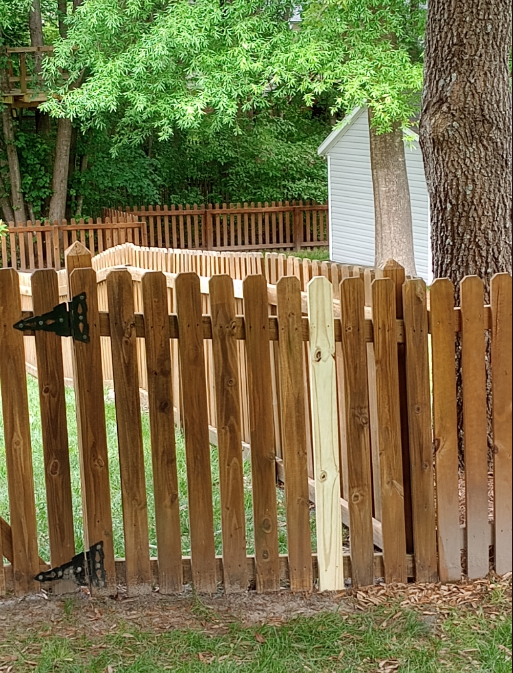 A wooden picket fence with a gate and a white house in the background