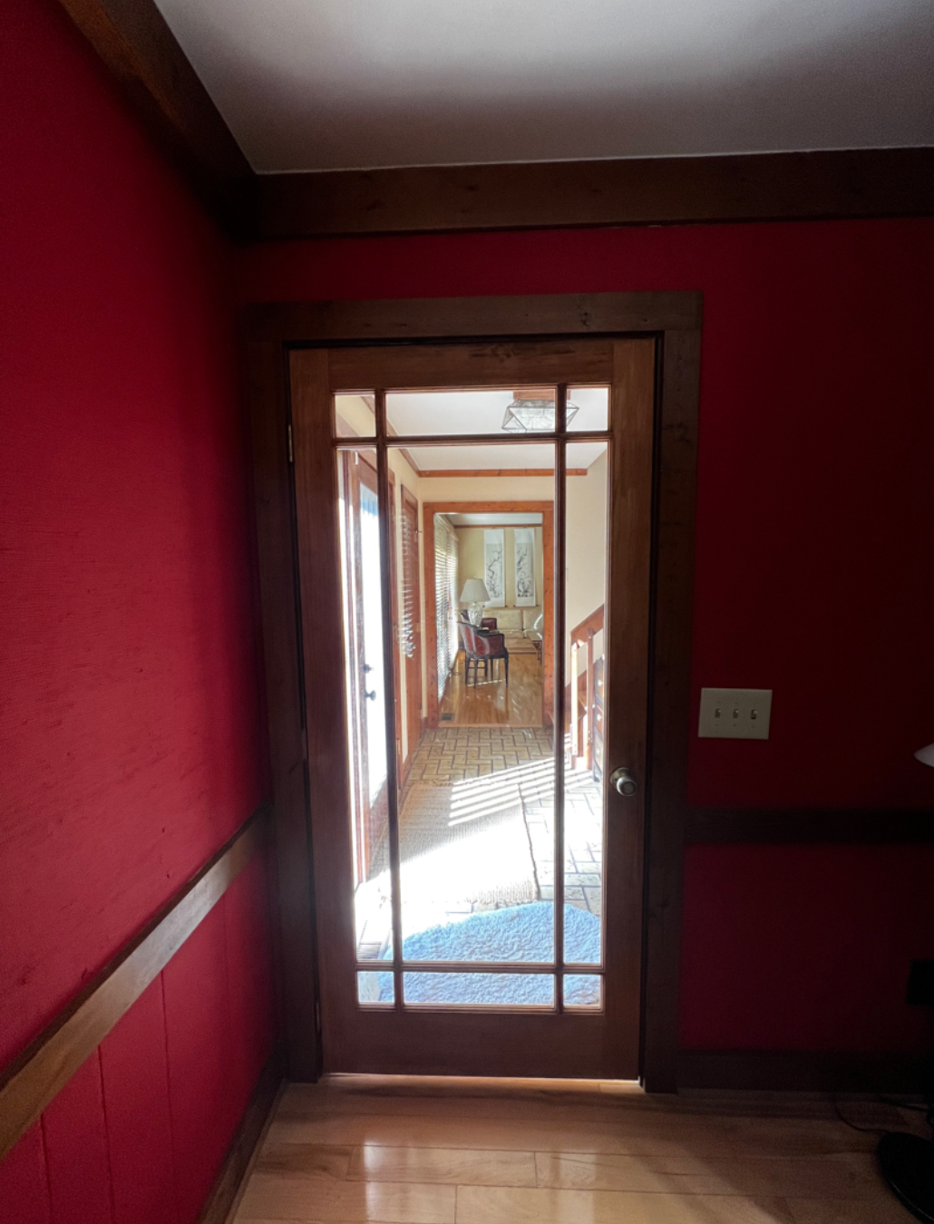 A hallway with red walls and a glass door