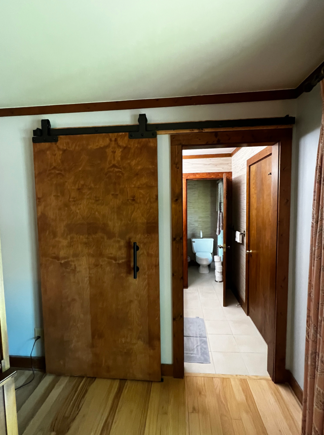 A bedroom with a sliding barn door leading to a bathroom.