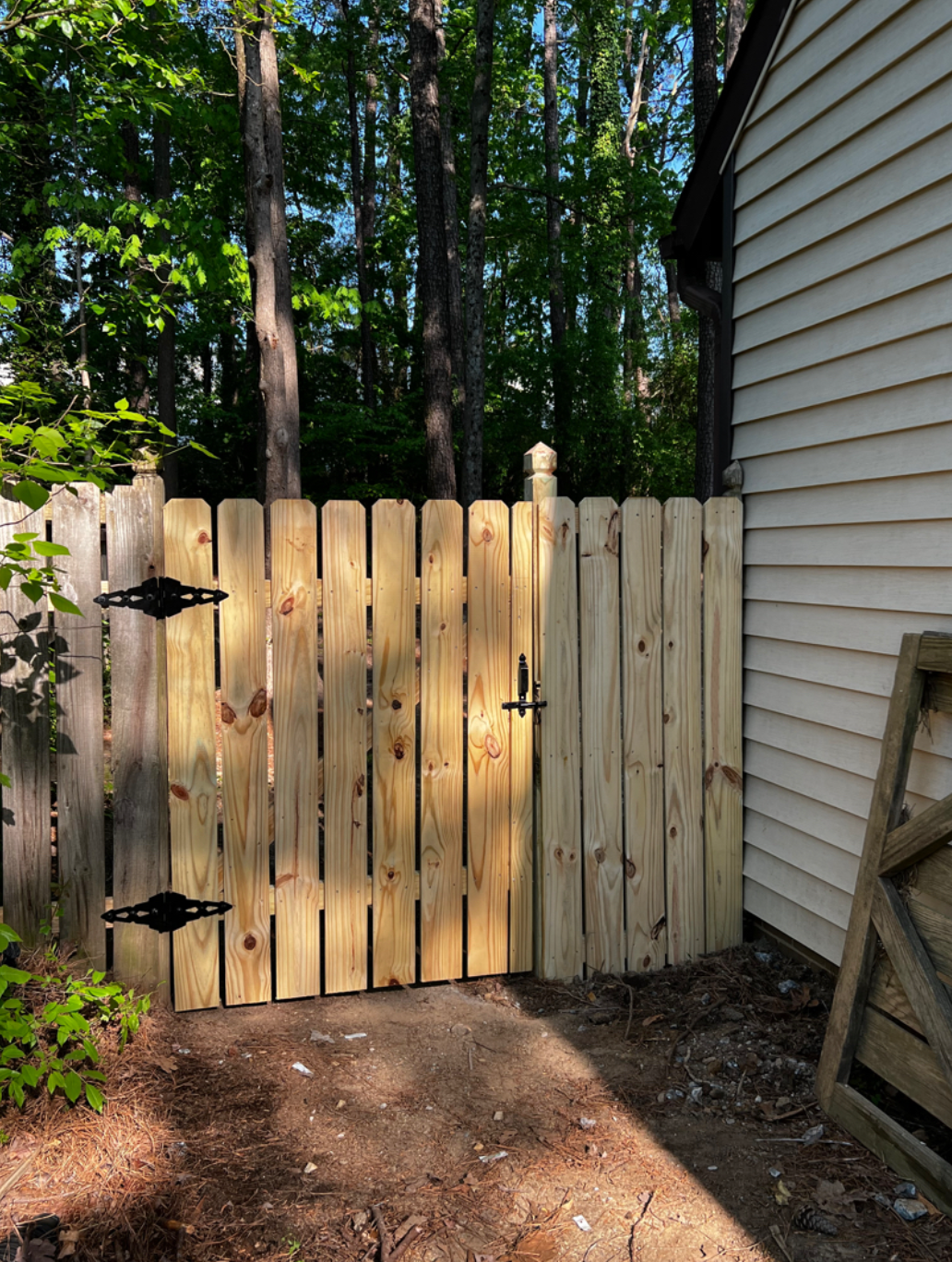 A wooden fence is next to a house in the woods