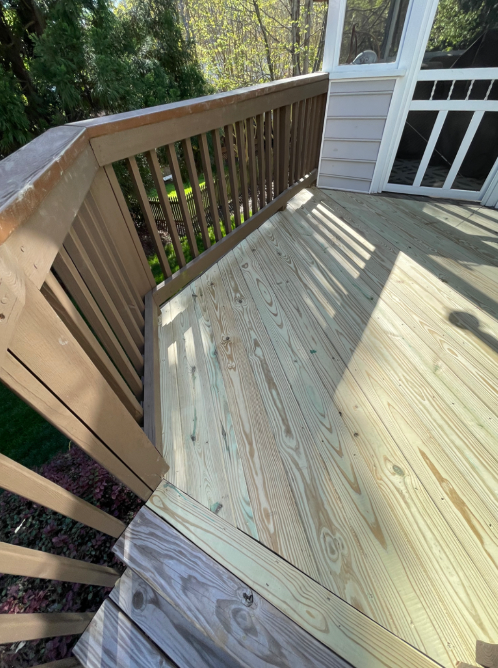 A wooden deck with a screened in porch and a wooden railing.
