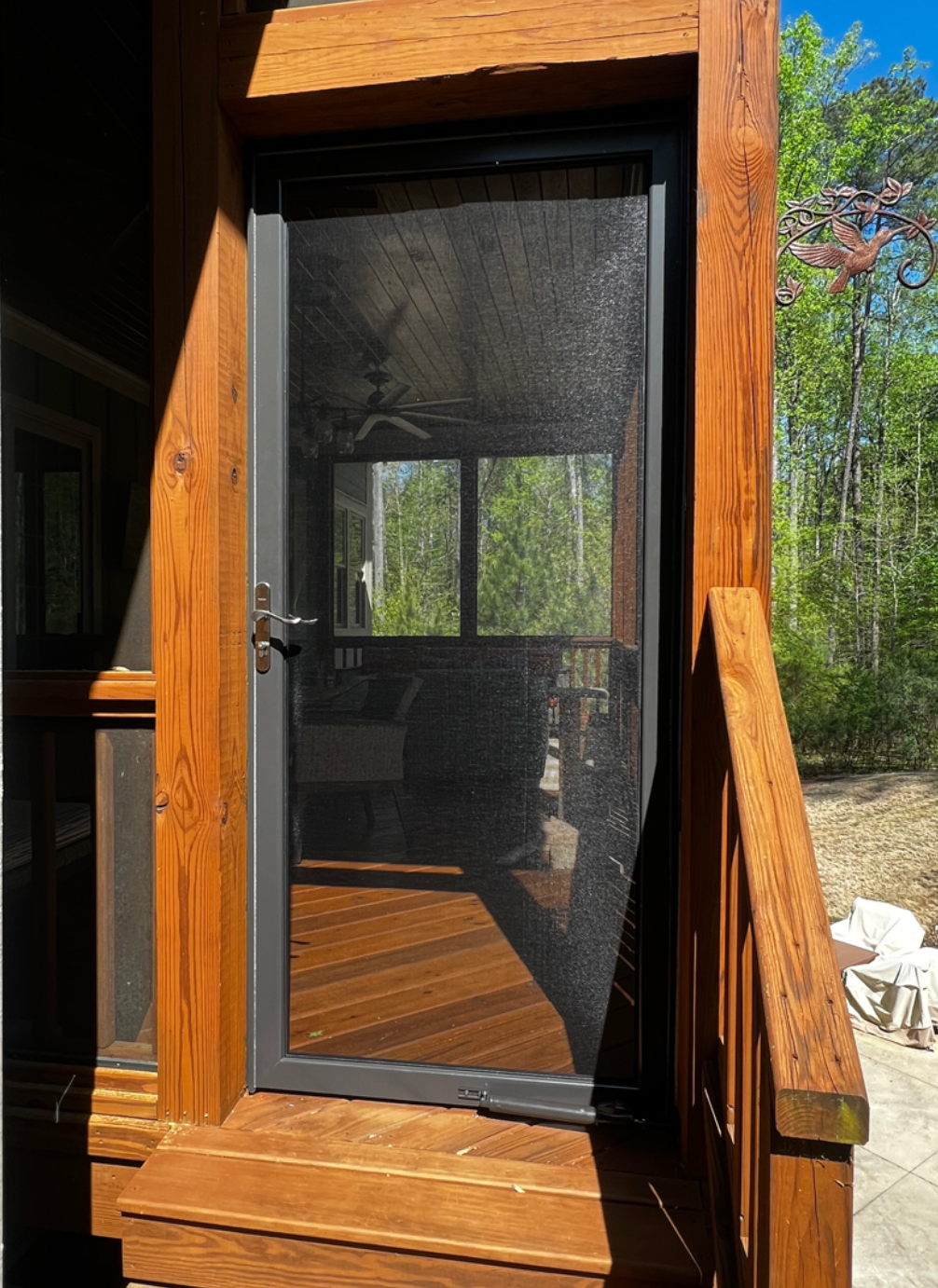 A screened in porch with a wooden deck and stairs