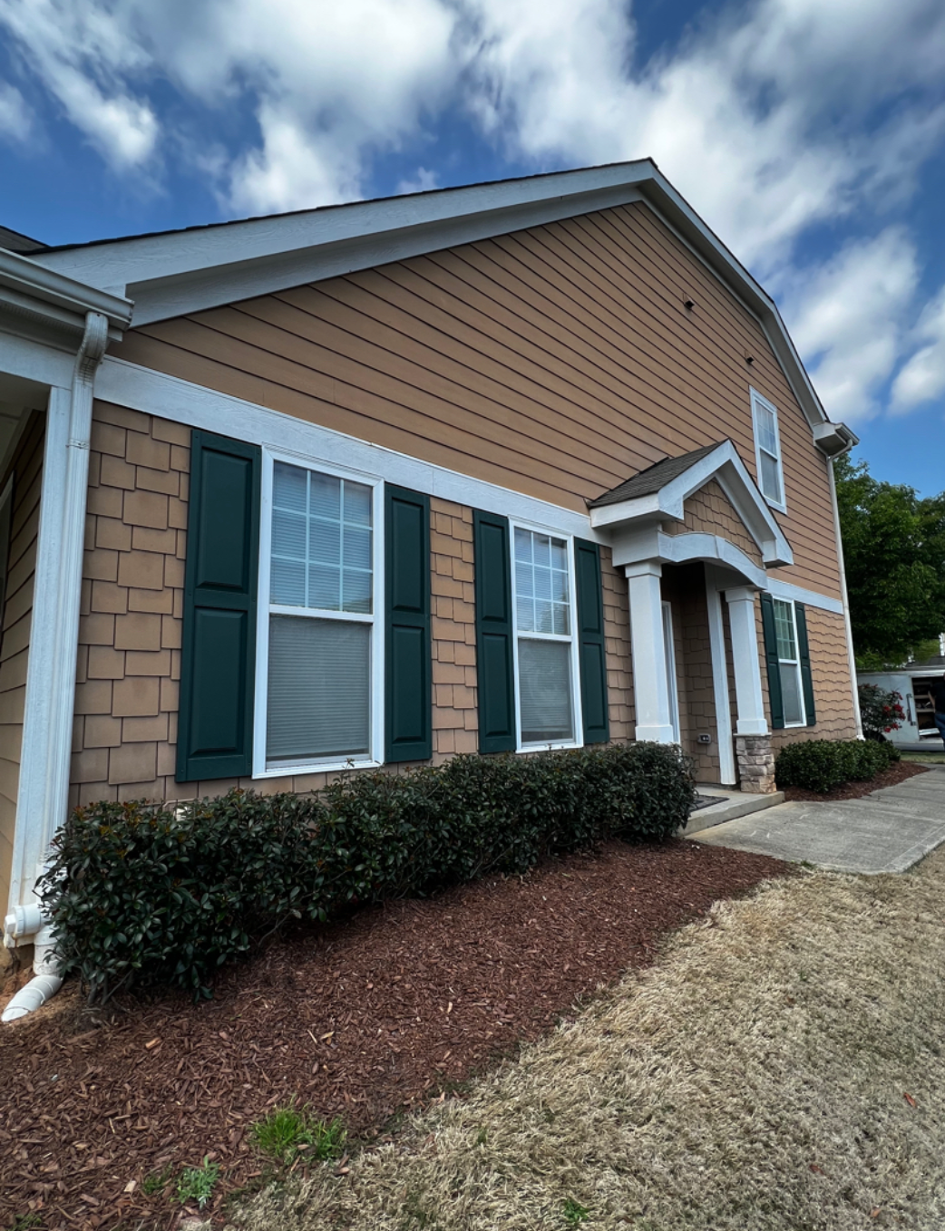 A house with a lot of windows and green shutters.