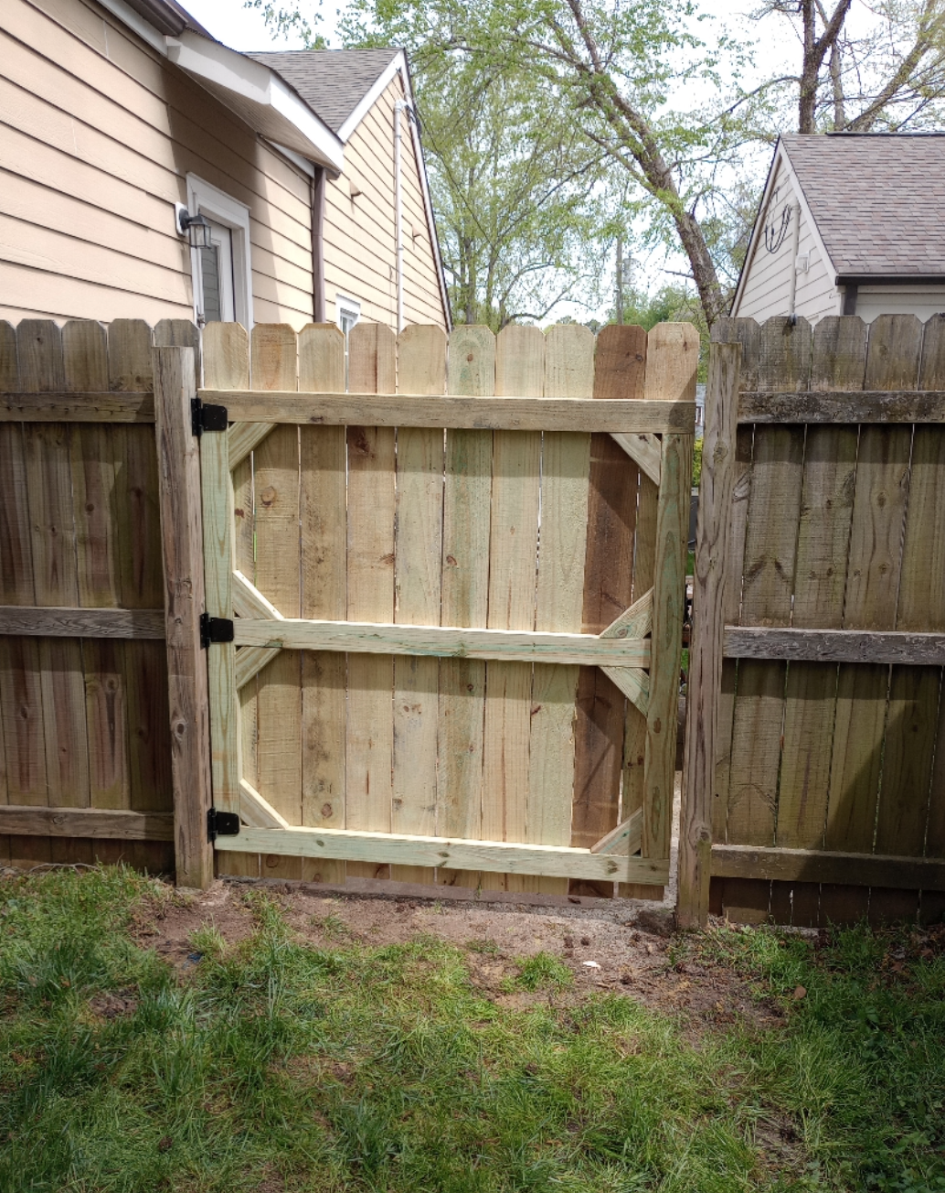 A wooden fence with a wooden gate in the backyard