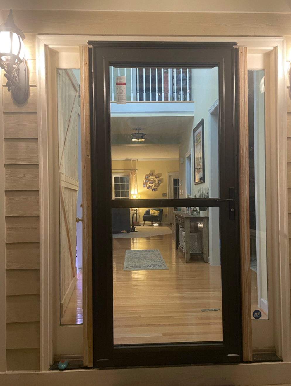 A black door is open to a living room in a house.