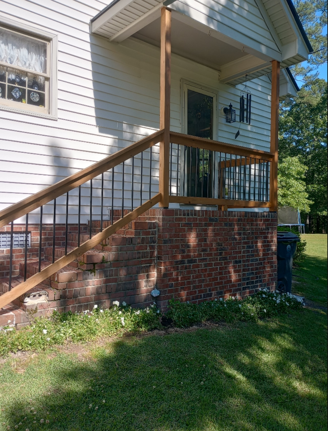 A white house with a wooden porch and stairs leading up to it.
