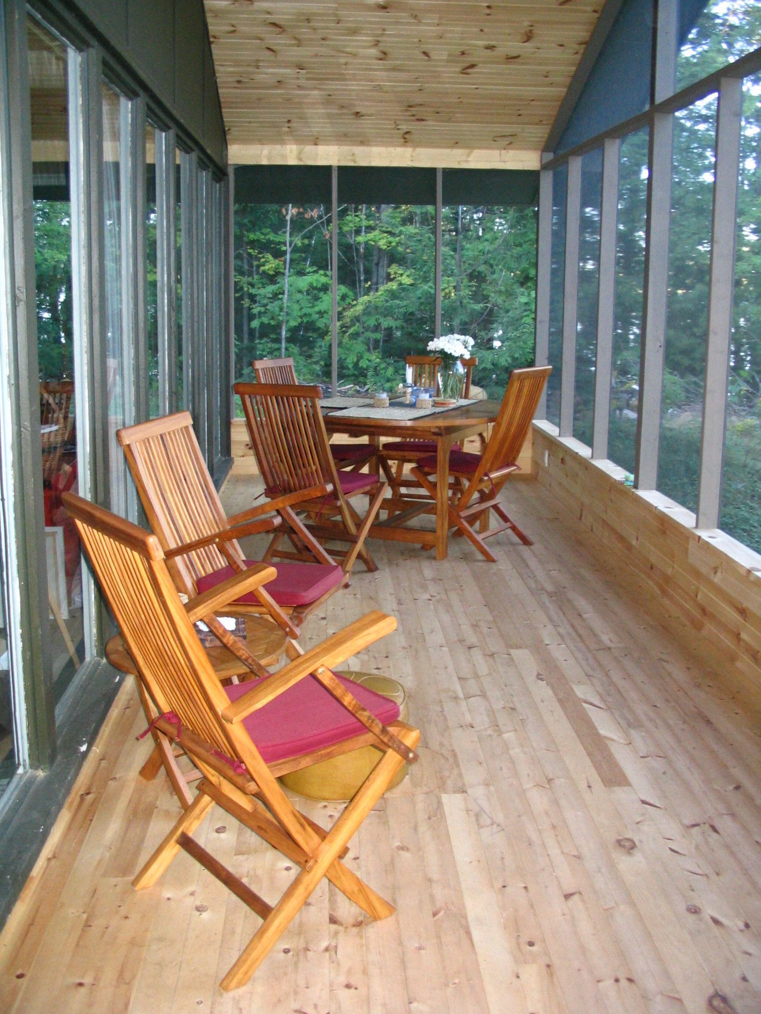 A screened in porch with a table and chairs