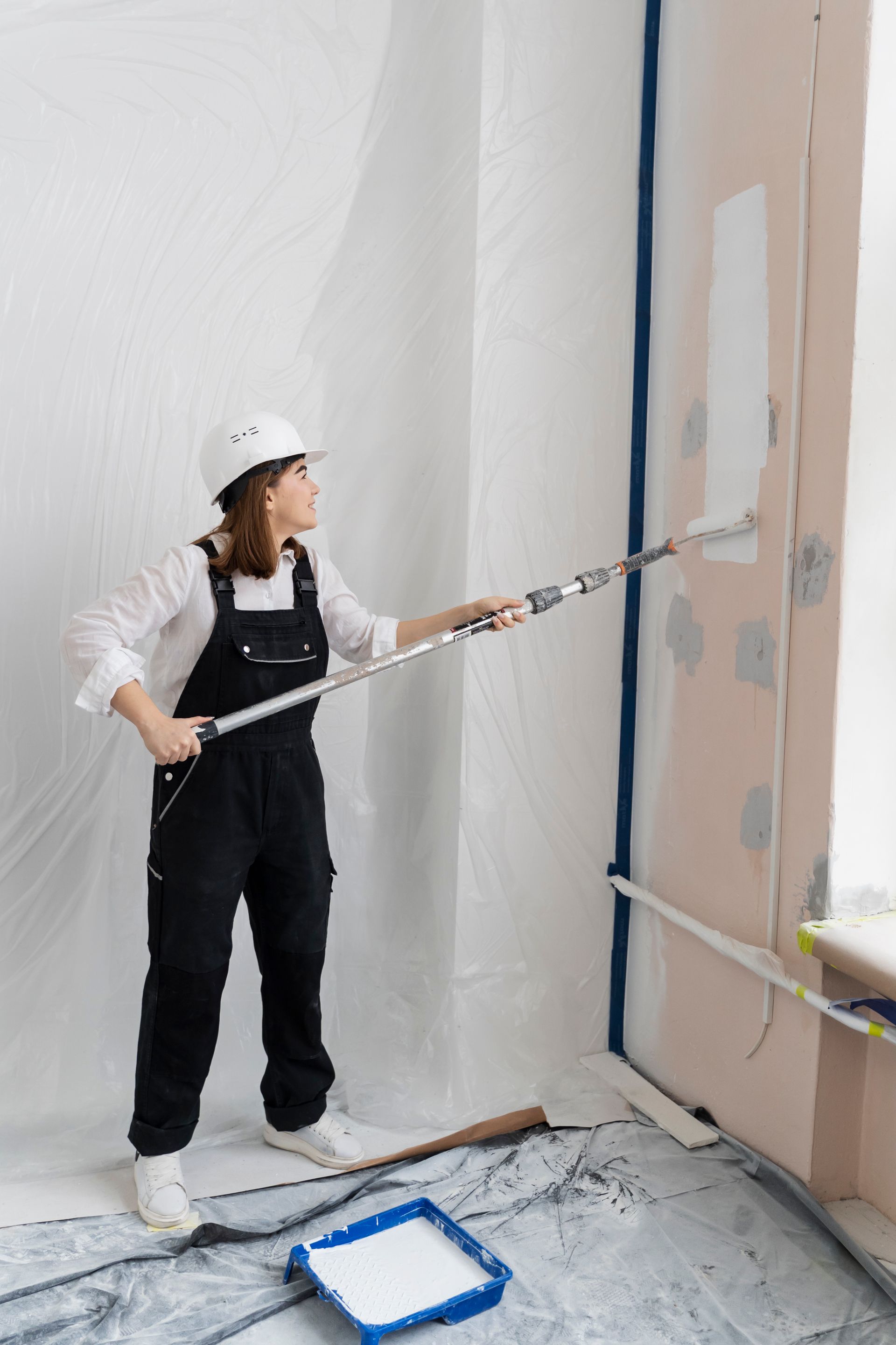 A woman is painting a wall with a paint roller.