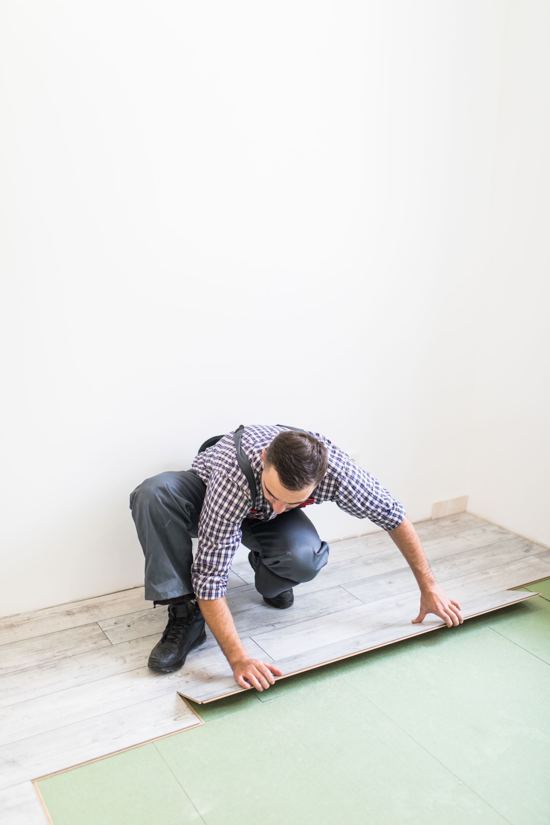 A man is installing a wooden floor in a room.
