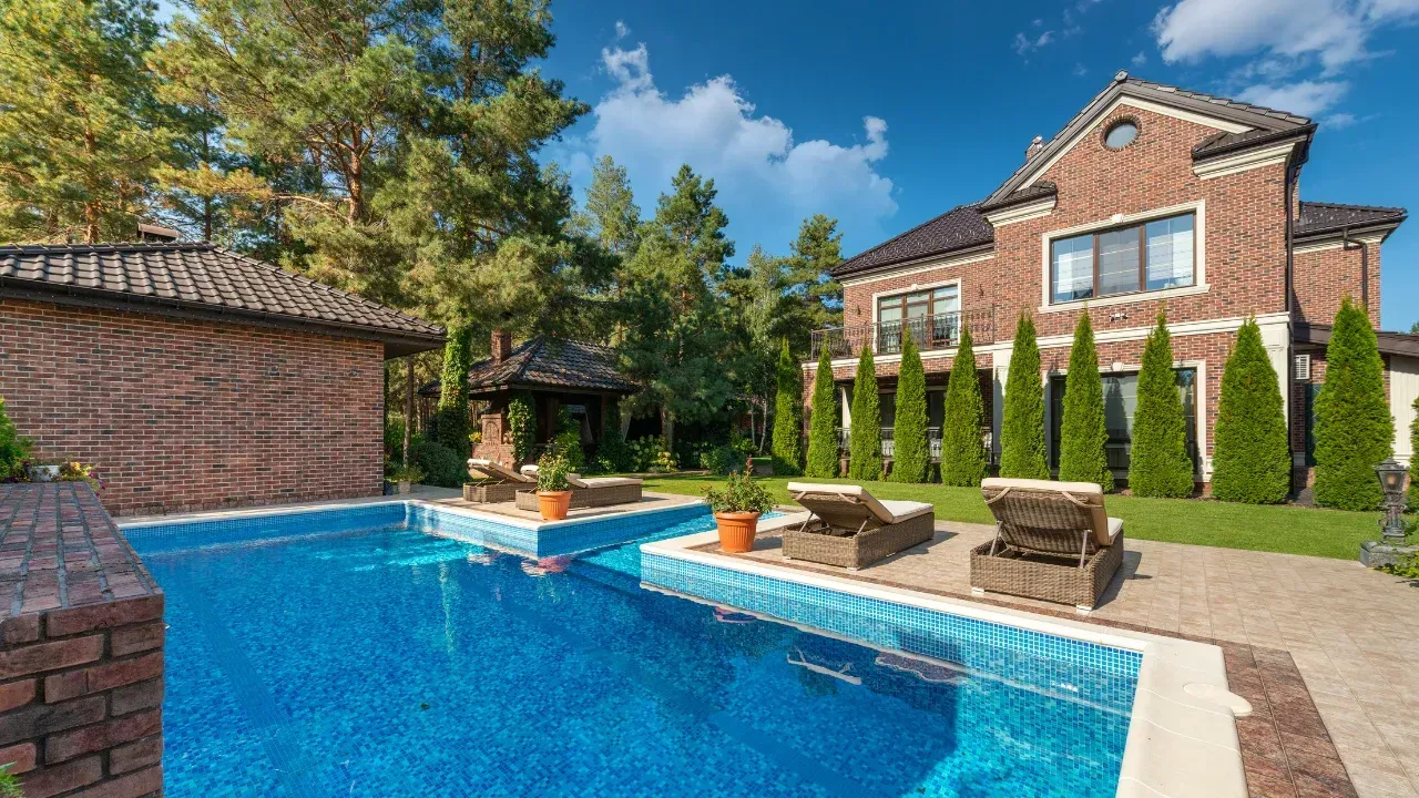 A house with a pool in the backyard and concrete patio