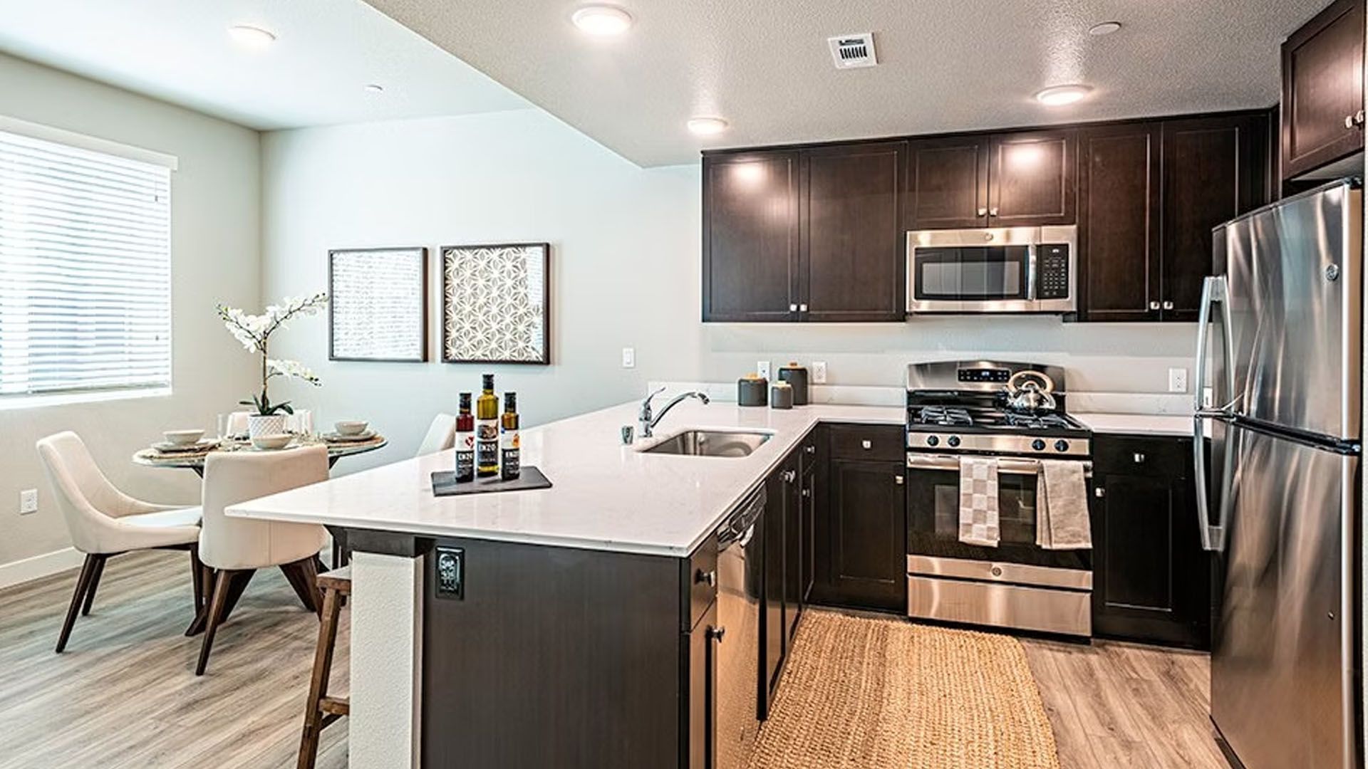 Modern kitchen with dark brown cabinets, stainless steel appliances, and white countertop.