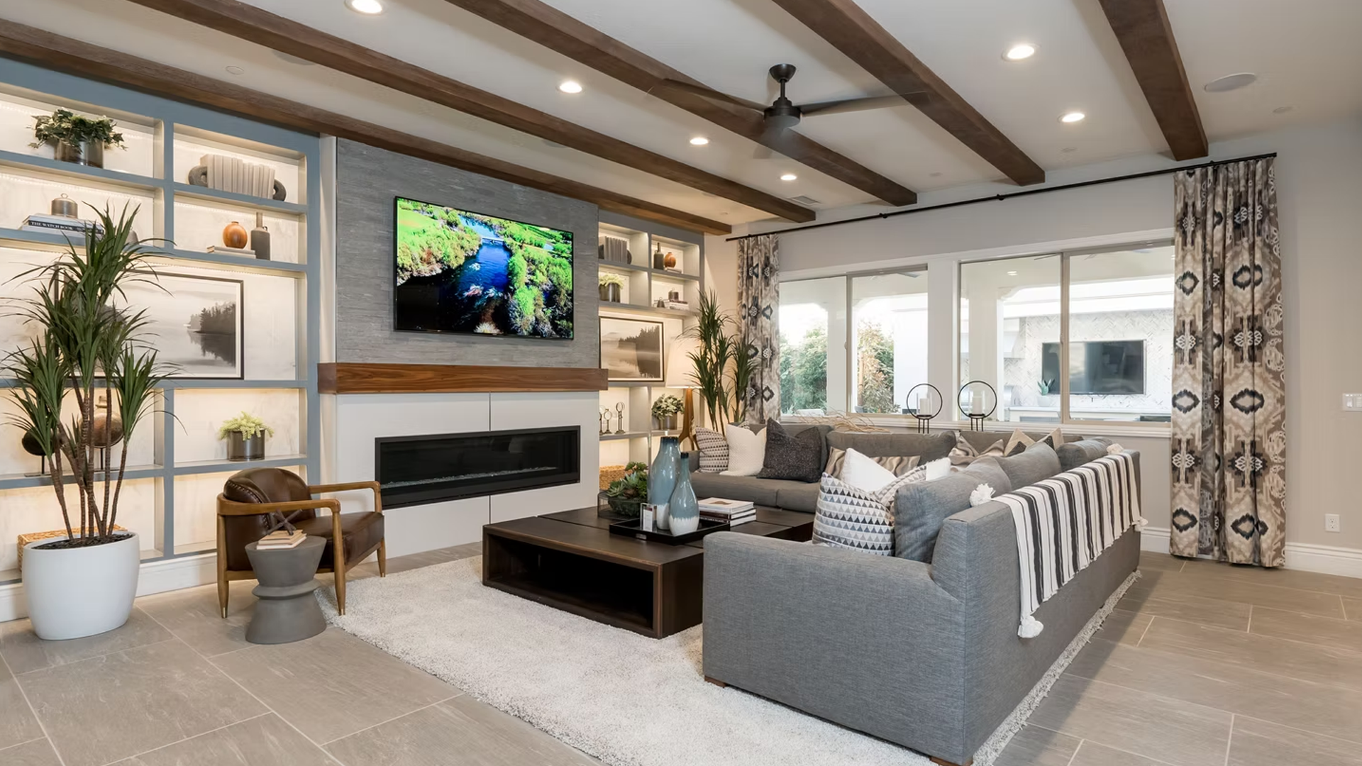 Living room with gray sofa, fireplace, bookshelves, and large windows.