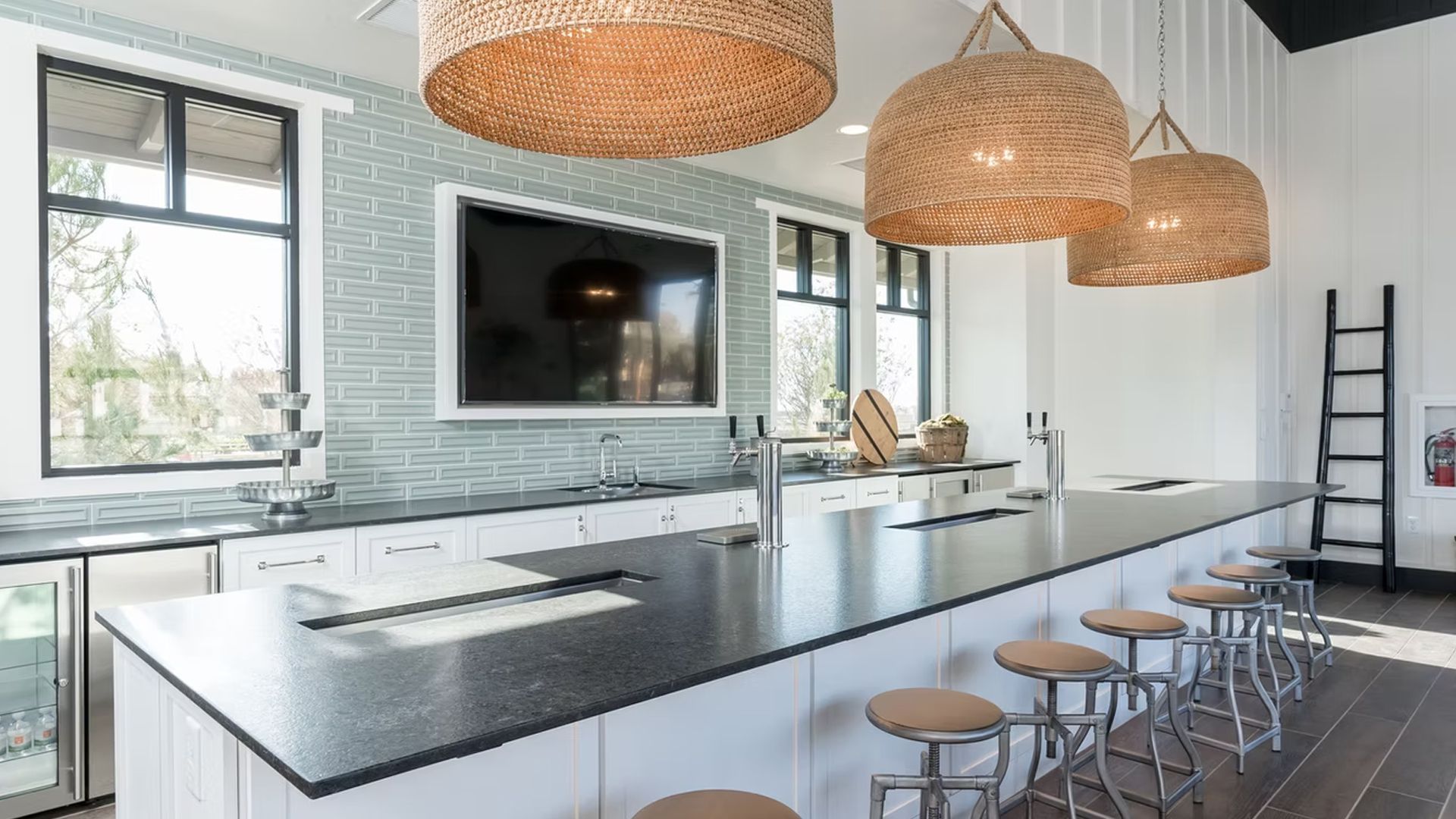 Kitchen bar area with black countertops, white cabinets, and woven pendant lights.