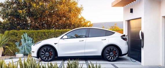 White Tesla Model Y charging at home.