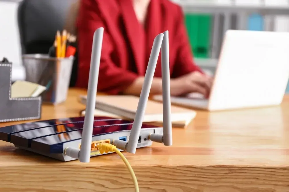 Wifi Router With Three Antennas on a Desk, Connected to a Laptop With Person — Superior Wifi in Lennox Head, NSW