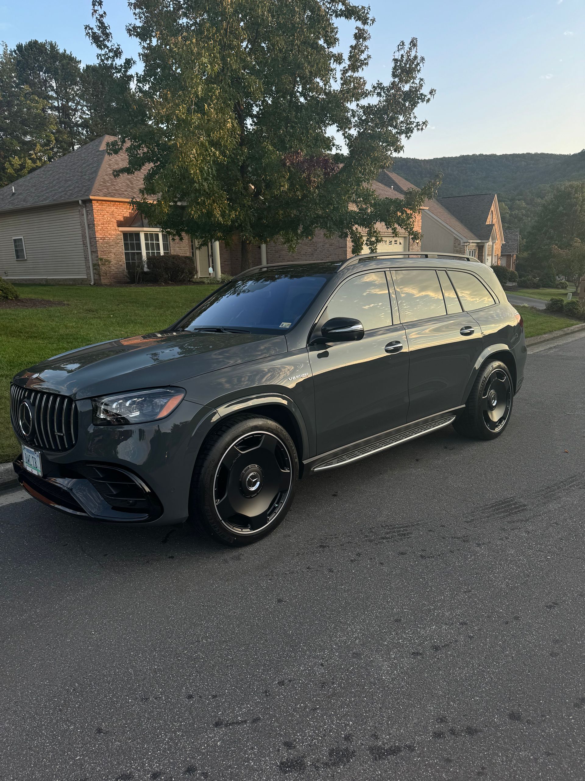 Dark gray SUV parked on a quiet road beside houses and trees at sunset