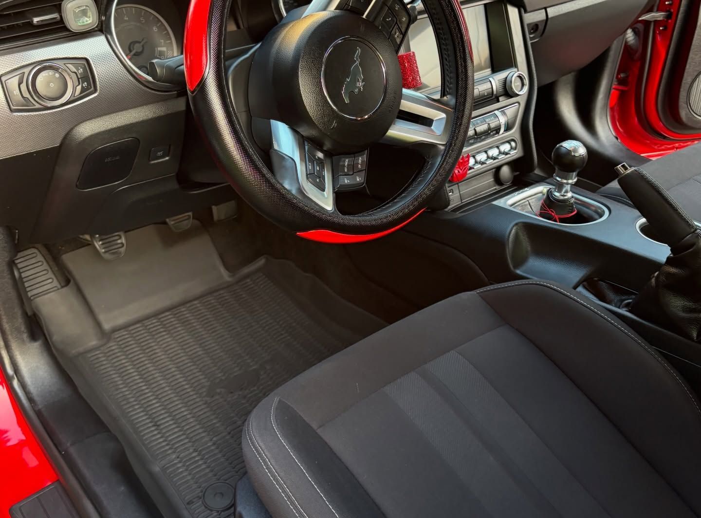 Gloved hand cleaning a car’s gear shift and center console with a brush