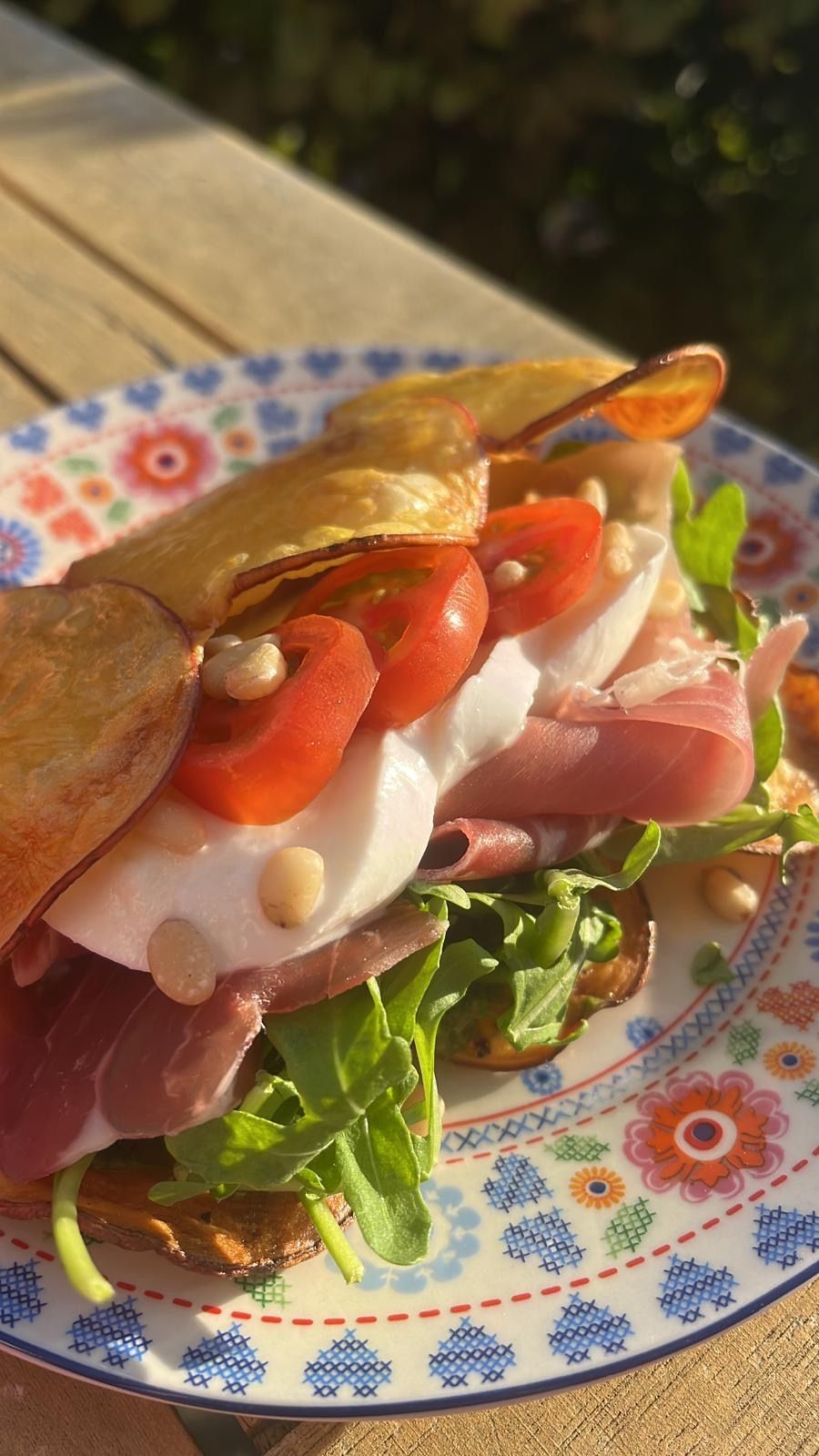 Een luxe sandwich met ham, mozzarella, tomaten en rucola, geserveerd op aardappelchips-