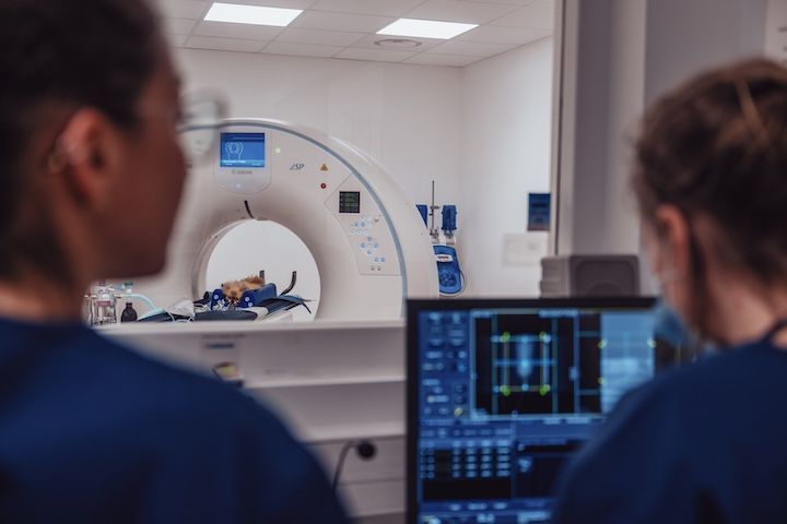 Deux infirmières regardent un écran d'ordinateur devant un scanner.