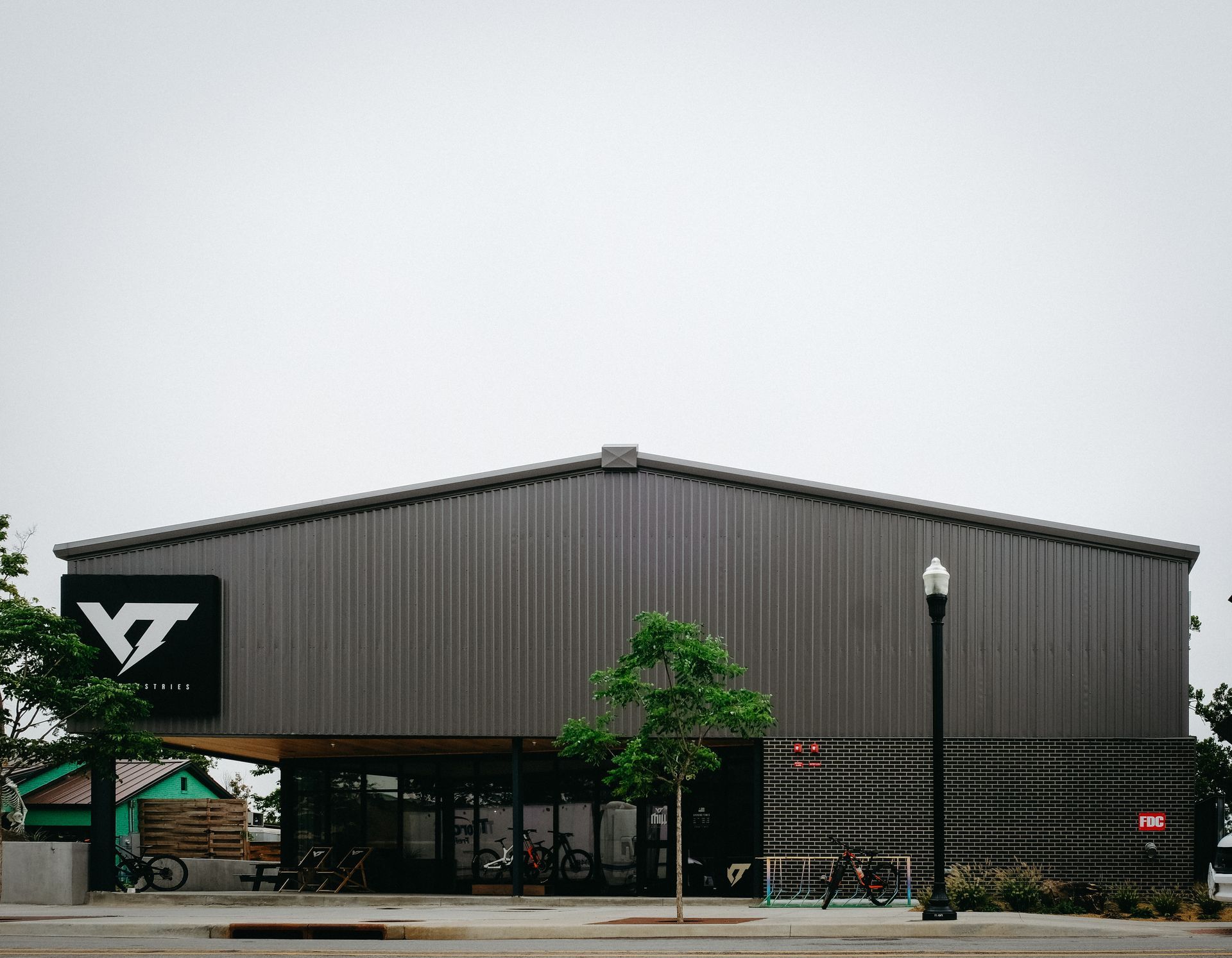 Bike shop building with gray metal siding and large logo; overcast sky.