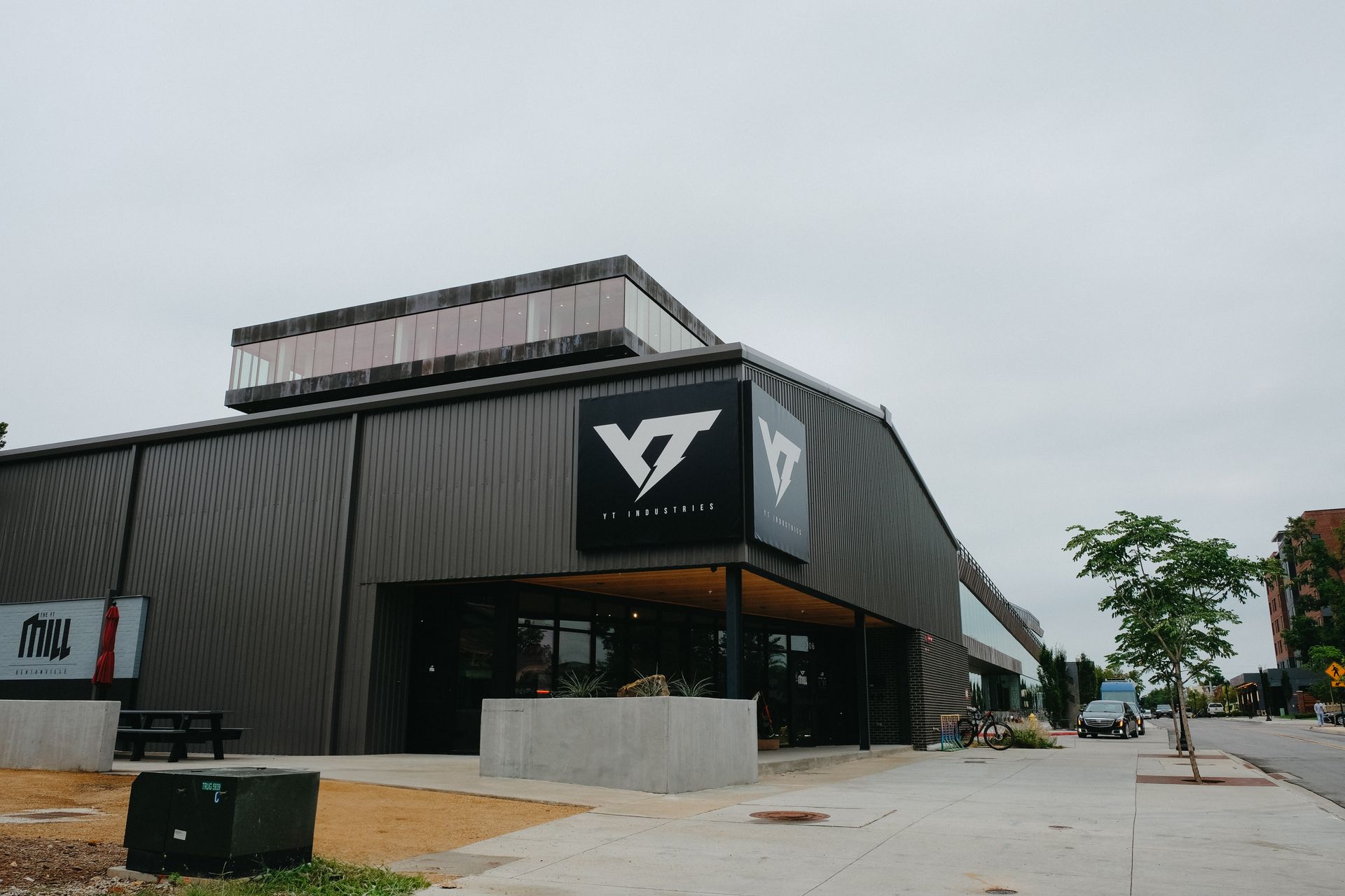 Exterior of a modern building with a dark logo, likely a business, under a cloudy sky.