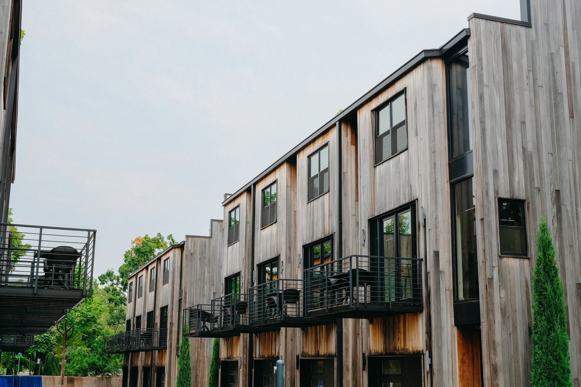 Row of modern townhomes with weathered wood siding and black balconies.