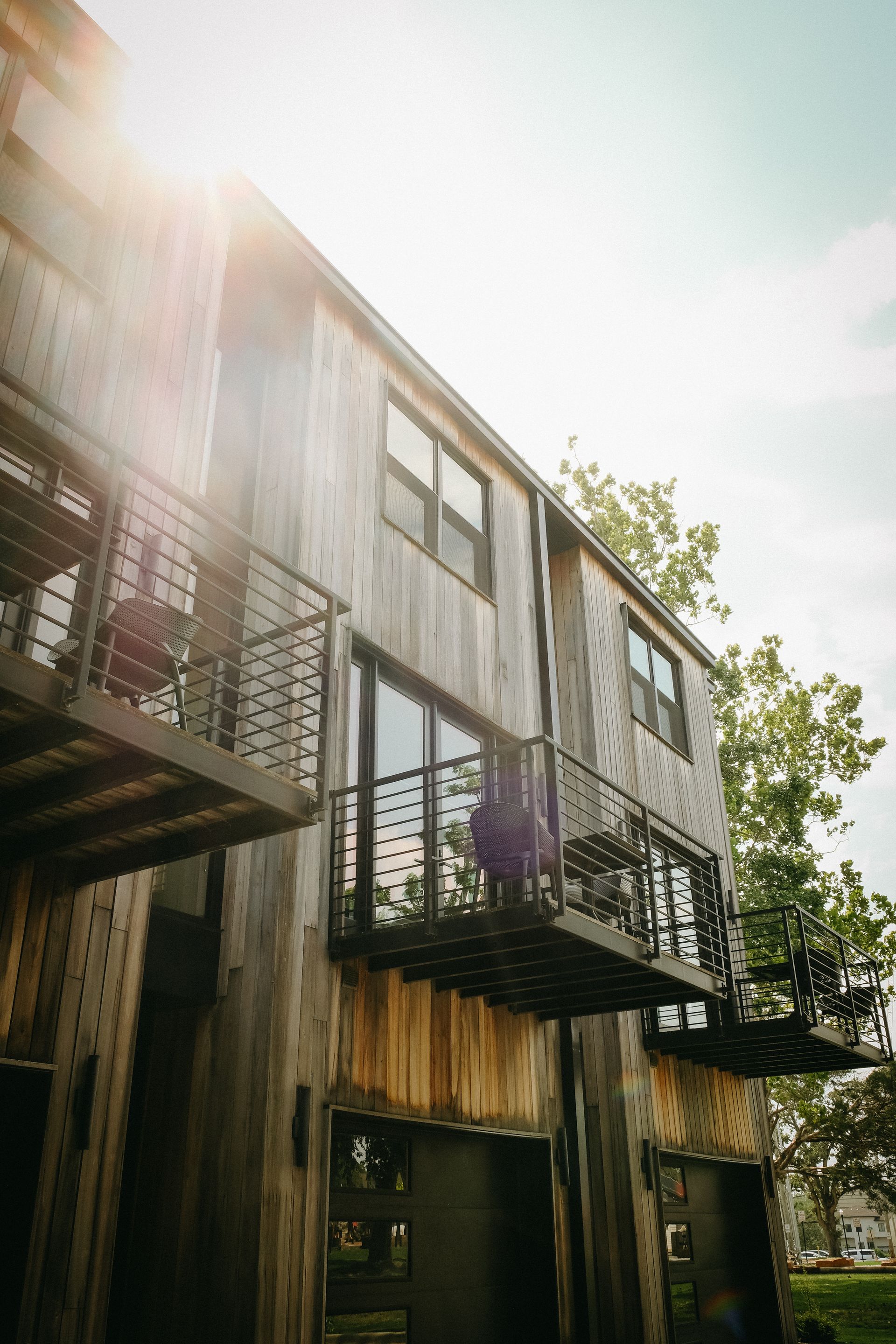 Two-story wooden building with balconies and sunlight.