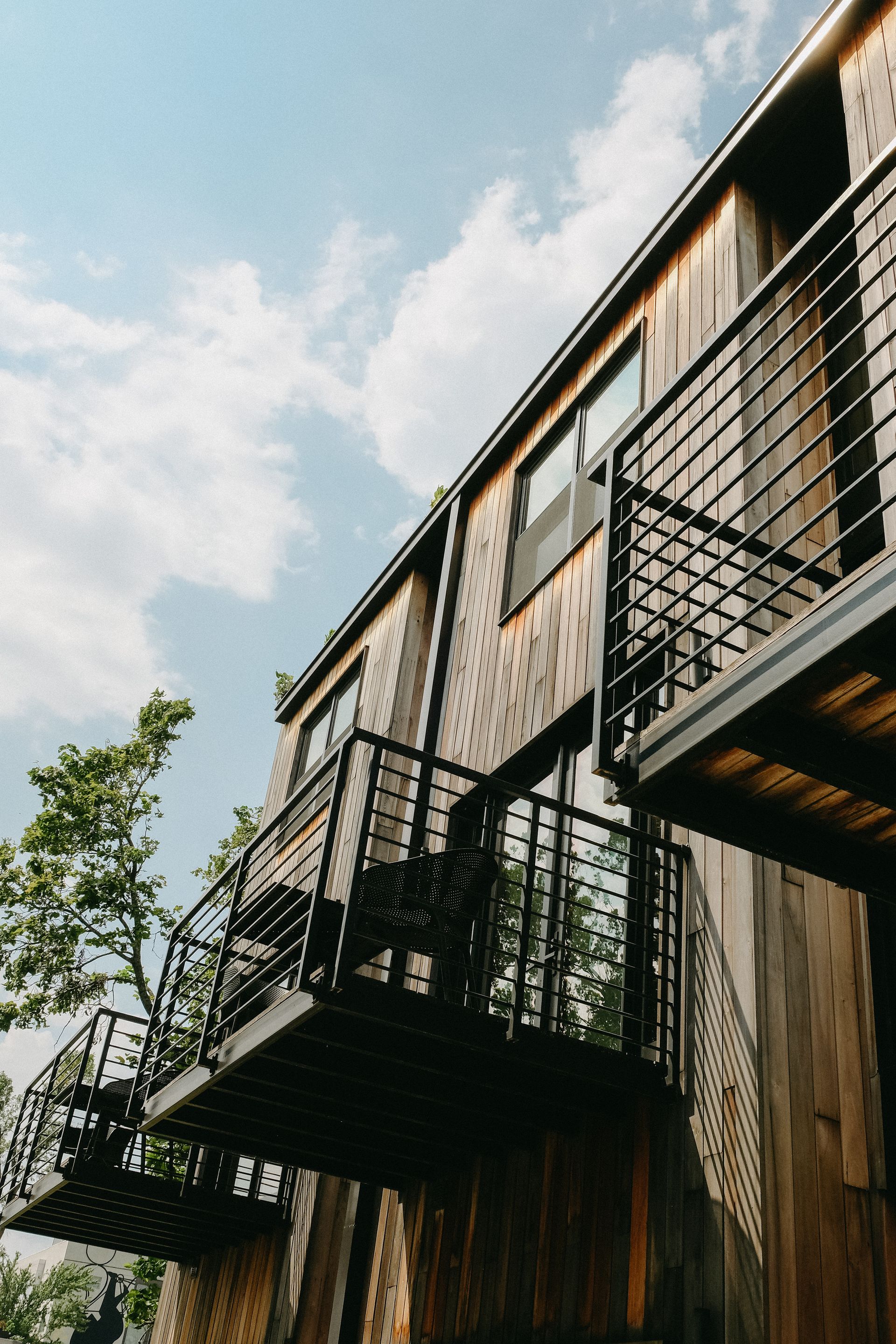 Wooden building with black balconies against a cloudy sky.