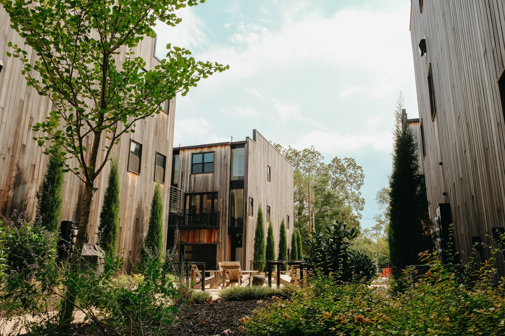 Wooden buildings with trees and greenery in an outdoor setting on a sunny day.
