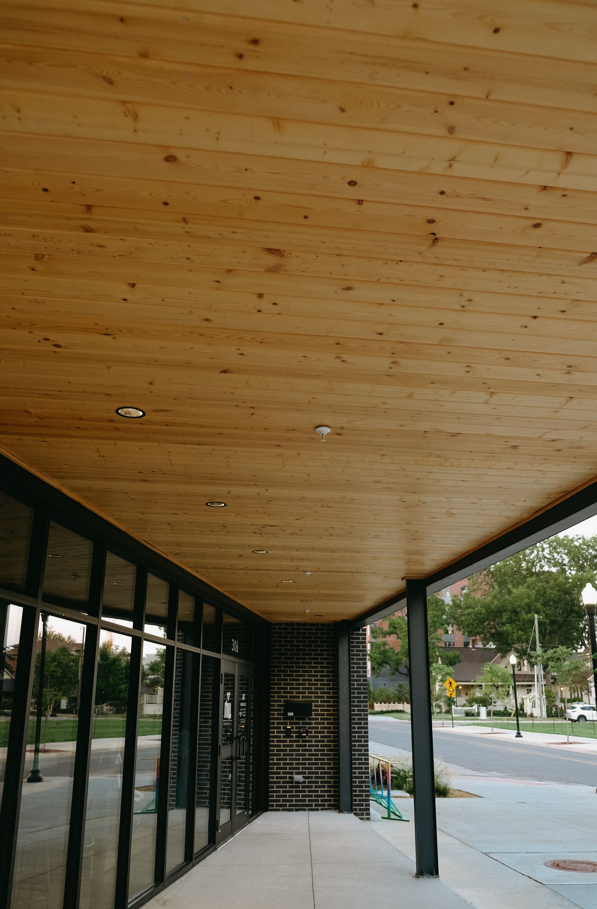 Wooden ceiling over a storefront with glass windows and a sidewalk.