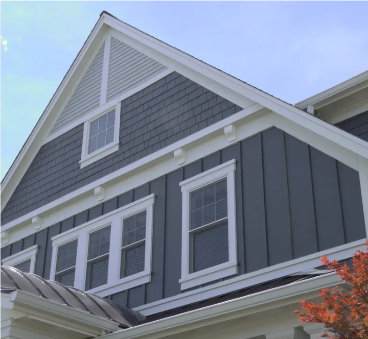 Gray house exterior with white trim and windows under a blue sky.