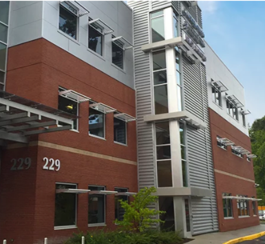Modern building with brick facade, metal accents, and window awnings; exterior.